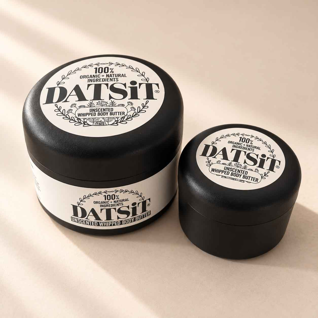Datsit Unscented Whipped Body Butter in 150ml and 50ml jars on a warm beige studio background